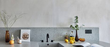 A kitchen counter with a sink, a book, and various kitchen items.