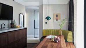 A modern kitchen with a wooden countertop, a flat-screen TV, and a dining area with a wooden table and a green sofa. - Staycity London Dalston (London)