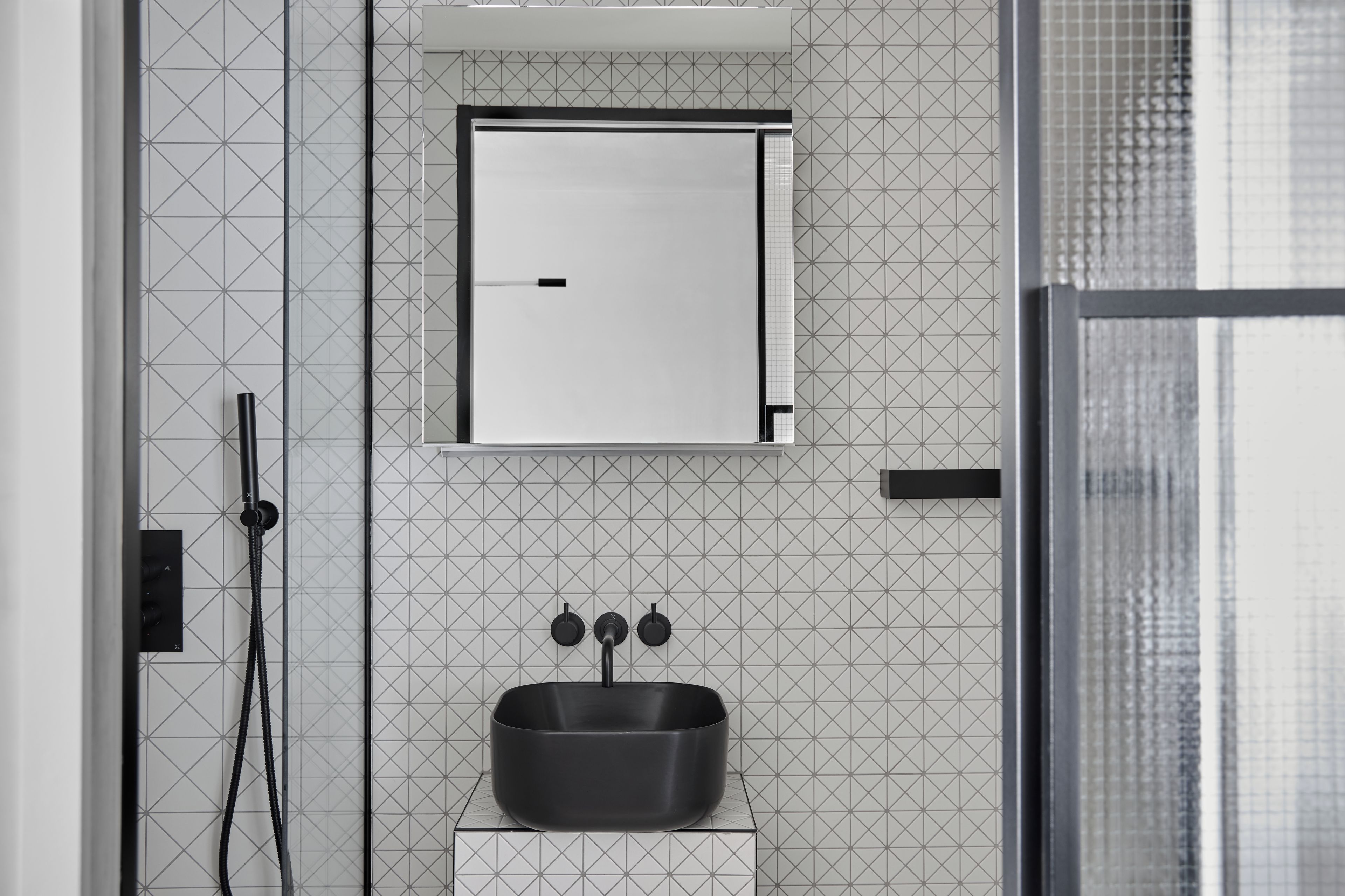 A bathroom with a black sink, a mirror, and a shower area.