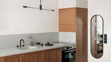 Cocina moderna con encimera de granito, electrodomésticos de acero inoxidable, armarios de madera y un espejo montado en la pared.
