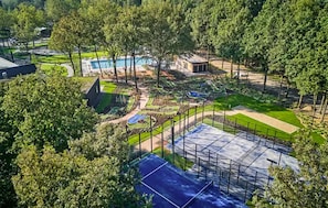Een woonwijk met een zwembad, tennisbanen en een omheind speelterrein.