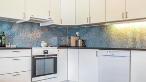 Eine moderne Küche mit weißen Schränken, einer Mikrowelle, einem Toaster und einem Wasserkocher.