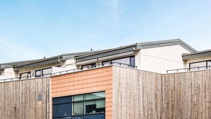 Ein modernes Gebäude mit flachem Dach, großen Fenstern und einer Holzfassade.