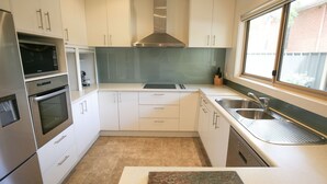 A modern kitchen with stainless steel appliances, white cabinetry, and a window providing natural light. - 22 RIVERSIDE : Bright (Bright)