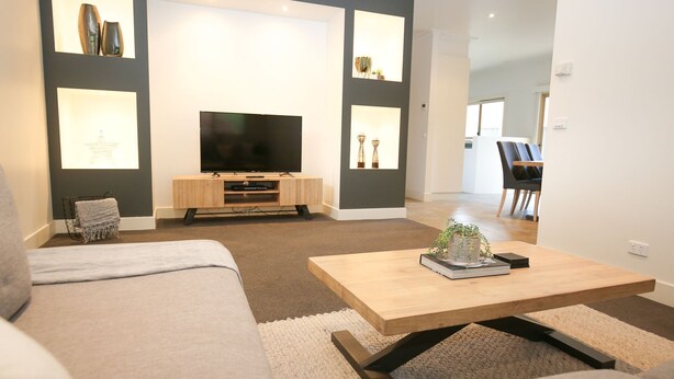 A modern living room with a flat-screen TV, a wooden coffee table, a sofa, and a dining area with chairs. - 22 RIVERSIDE : Bright (Bright)