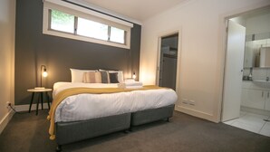 A modern bedroom with a large bed, bedside lamps, a small side table, and a walk-in closet. - 22 RIVERSIDE : Bright (Bright)