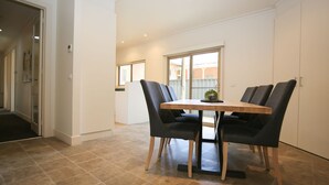 A dining area with a table and four chairs, a potted plant on the table, and a view of a brick building through a window. - 22 RIVERSIDE : Bright (Bright)
