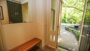 A hallway with a bench, a door with frosted glass panels, and a view of a garden. - 22 RIVERSIDE : Bright (Bright)