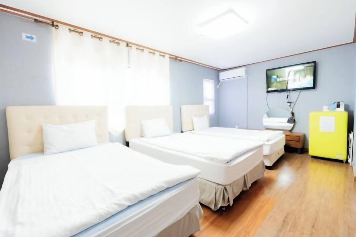 A hotel room with two beds, a television, a small table, and a yellow cabinet.