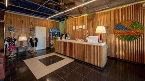 Een receptiebalie met een zwart-wit schaakbordvloer, houten lambrisering en een kleurrijke wanddecoratie.