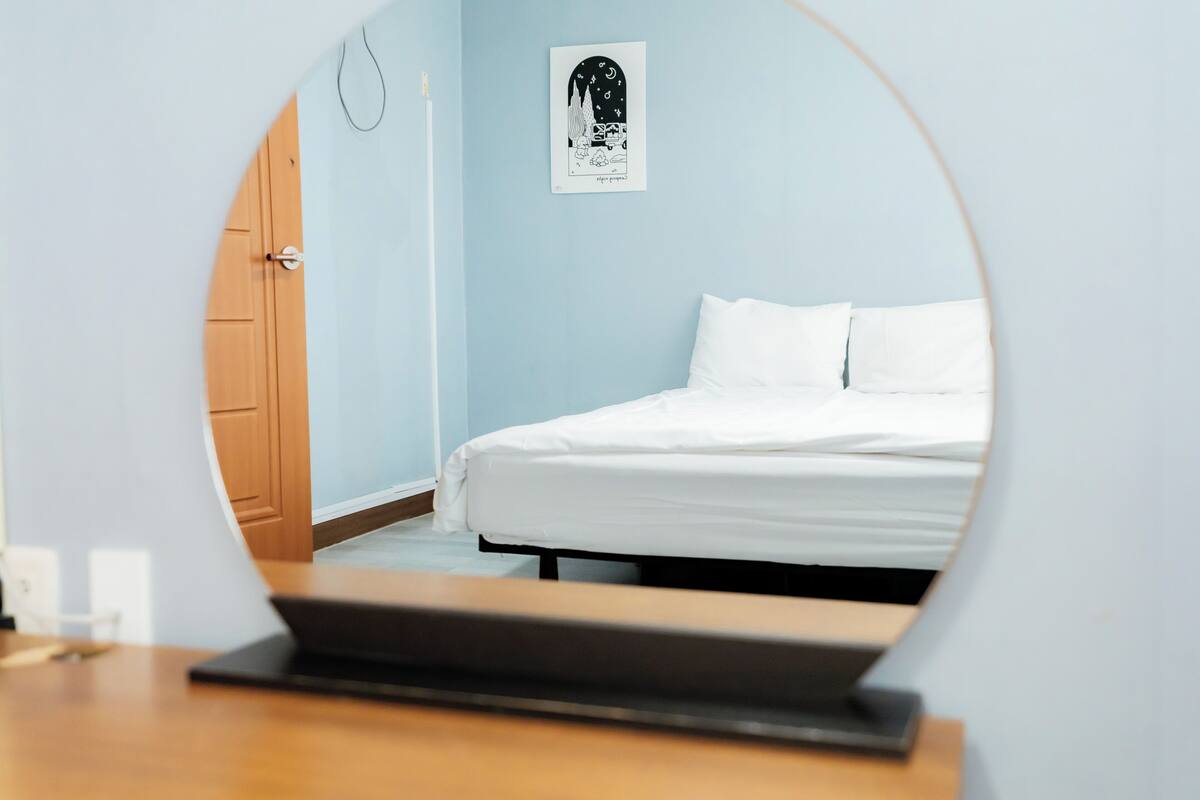 A bedroom with a bed, a door, and a wall-mounted artwork.