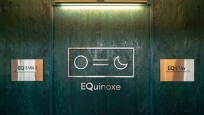 Een deur met de tekst 'EQinoxe' en twee borden ernaast, waarop 'EQ TABLE' en 'EQ STAY' staat.
