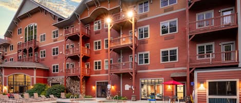 A multi-story hotel with a swimming pool, balconies, and outdoor seating areas.