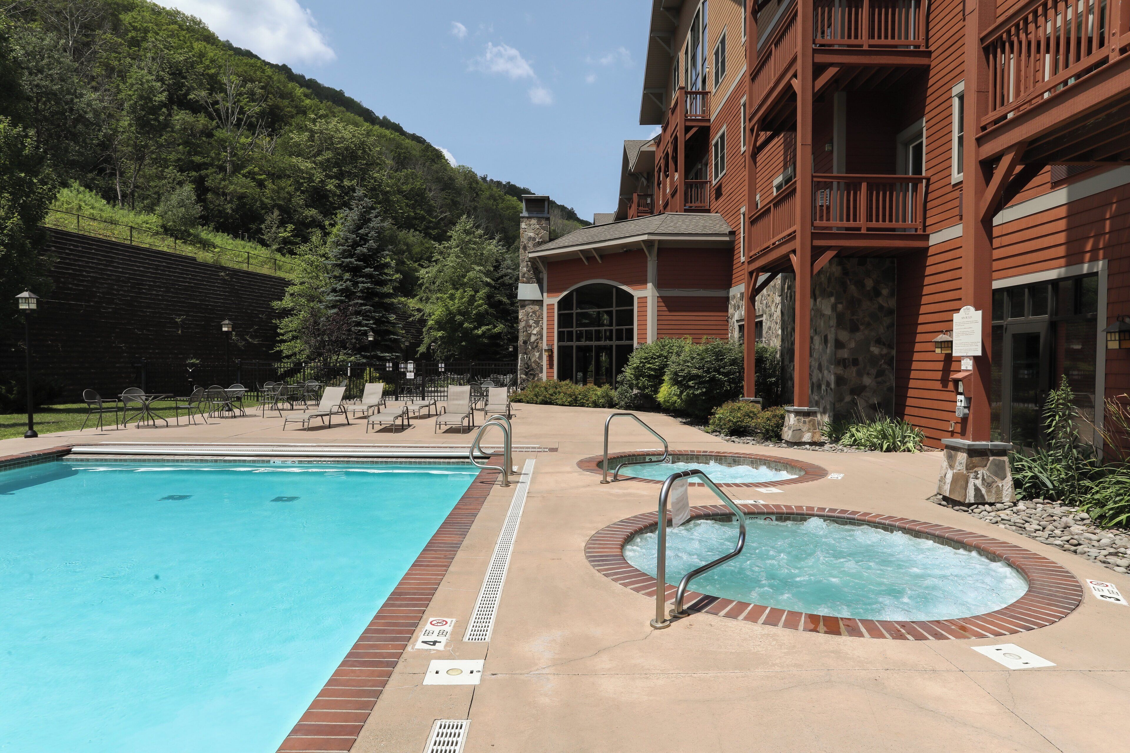 Un hotel con zona de piscina, que incluye una piscina grande y dos jacuzzis.