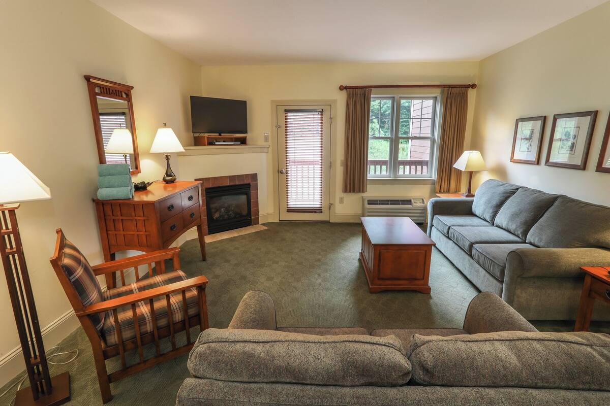 A living room with a fireplace, a sofa, a chair, and a television.