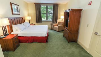 Une chambre d’hôtel avec un grand lit, une armoire en bois, un bureau avec une lampe, une chaise et un téléviseur.