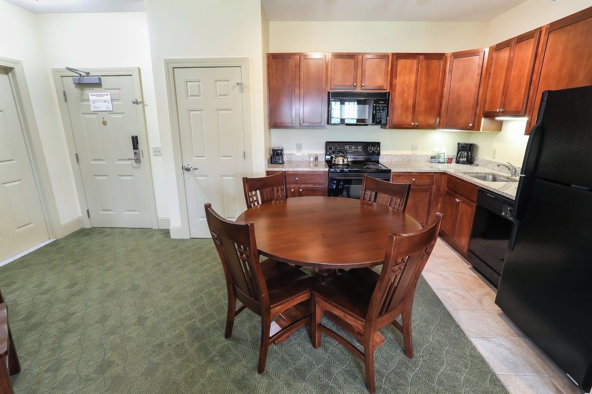 A compact kitchen with wooden cabinets, a microwave, a stove, and a refrigerator.