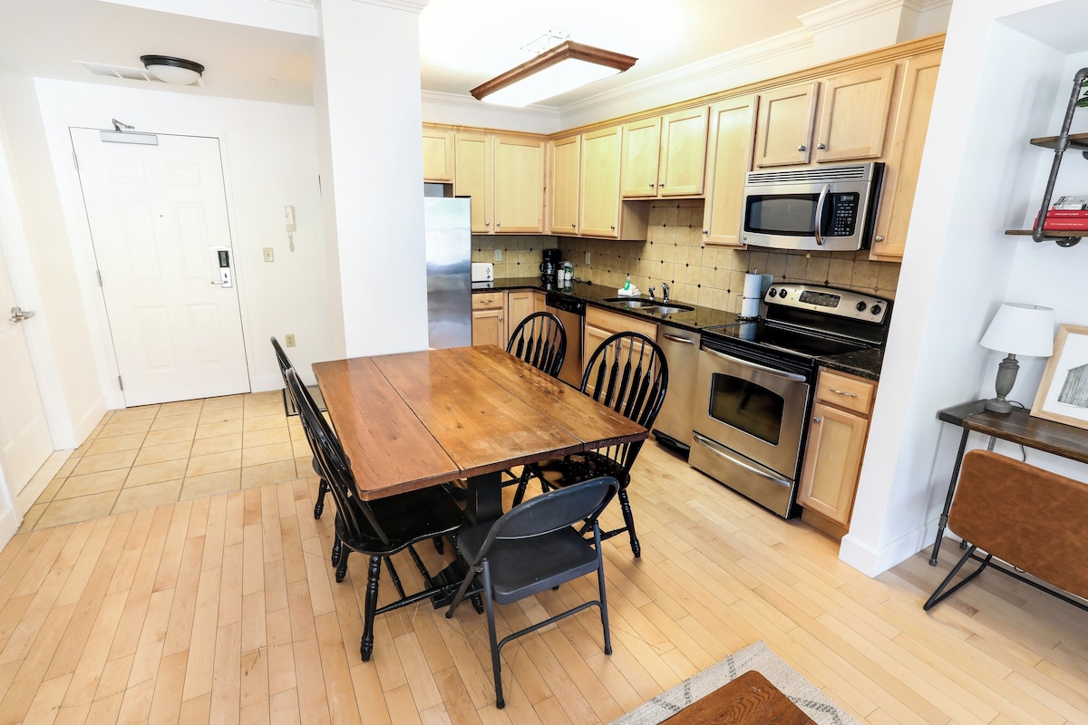 A modern kitchen with wooden cabinets, a stainless steel refrigerator, a microwave, and an oven.