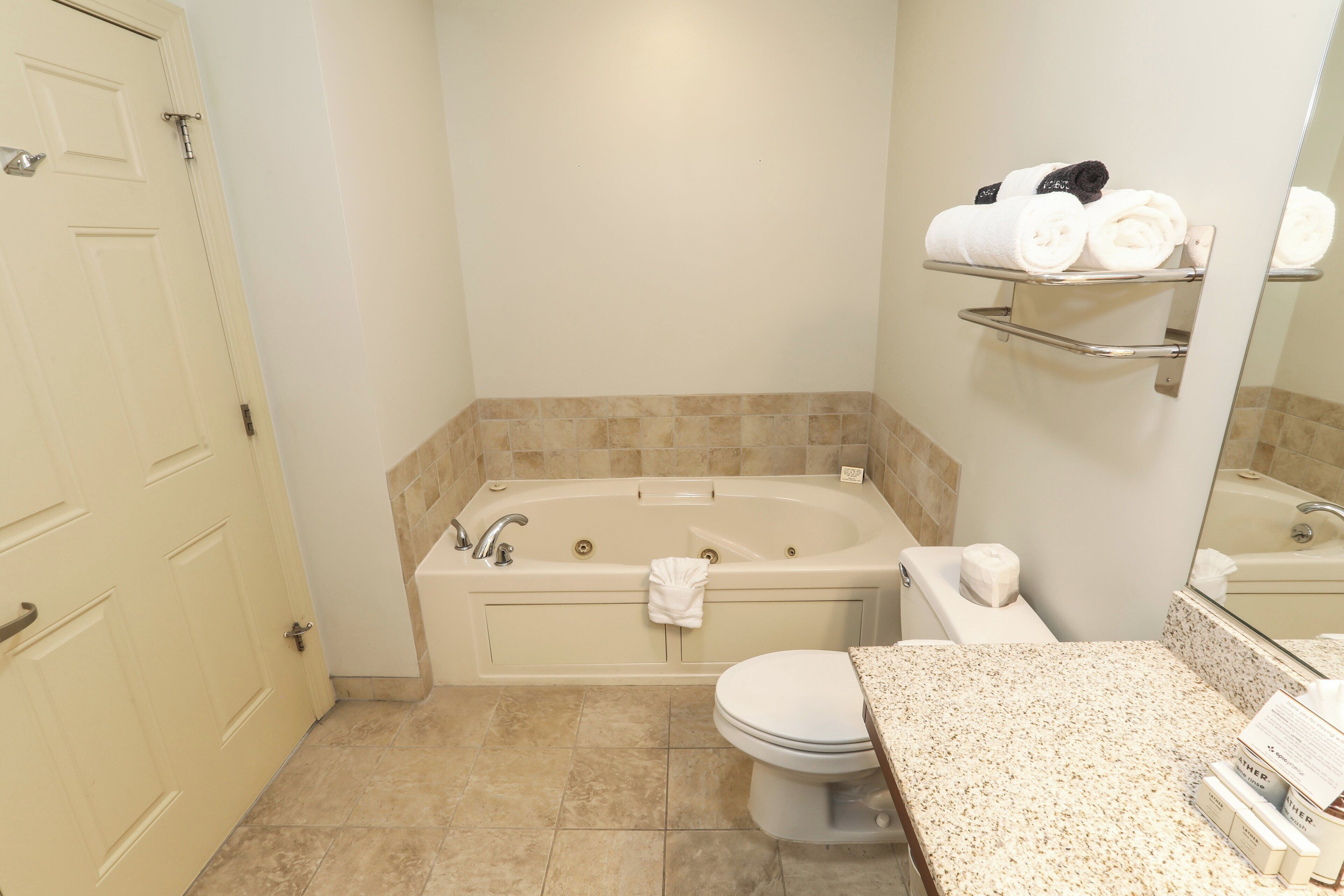 A bathroom with a bathtub, toilet, and a sink with a towel rack.