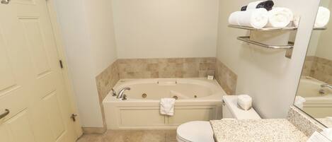 A bathroom with a bathtub, toilet, and a sink with a towel rack.