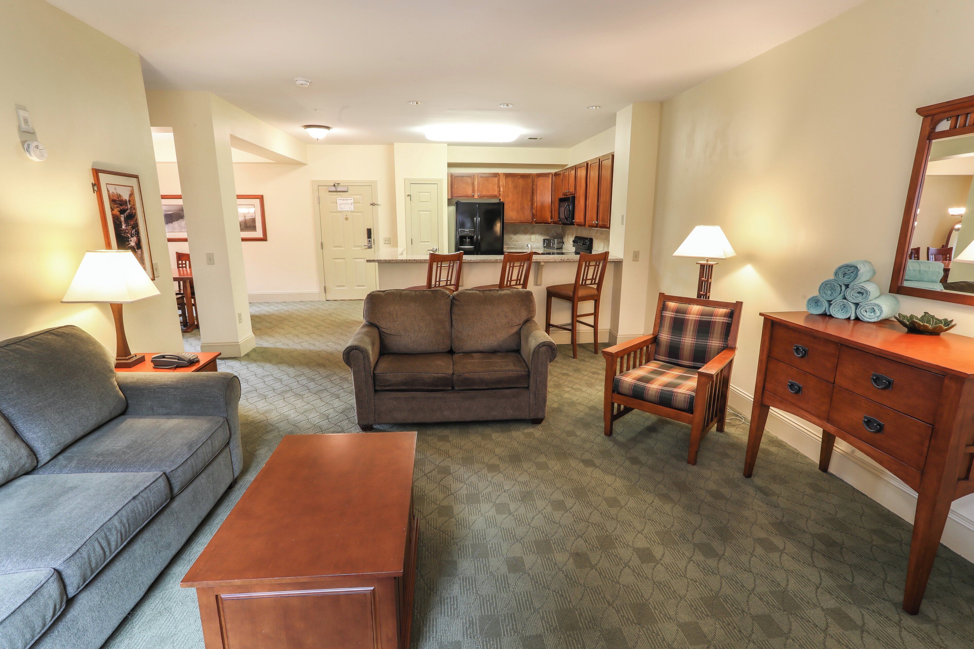 A living room with a sofa, a loveseat, a coffee table, a dining area with a table and chairs, and a kitchen in the background.