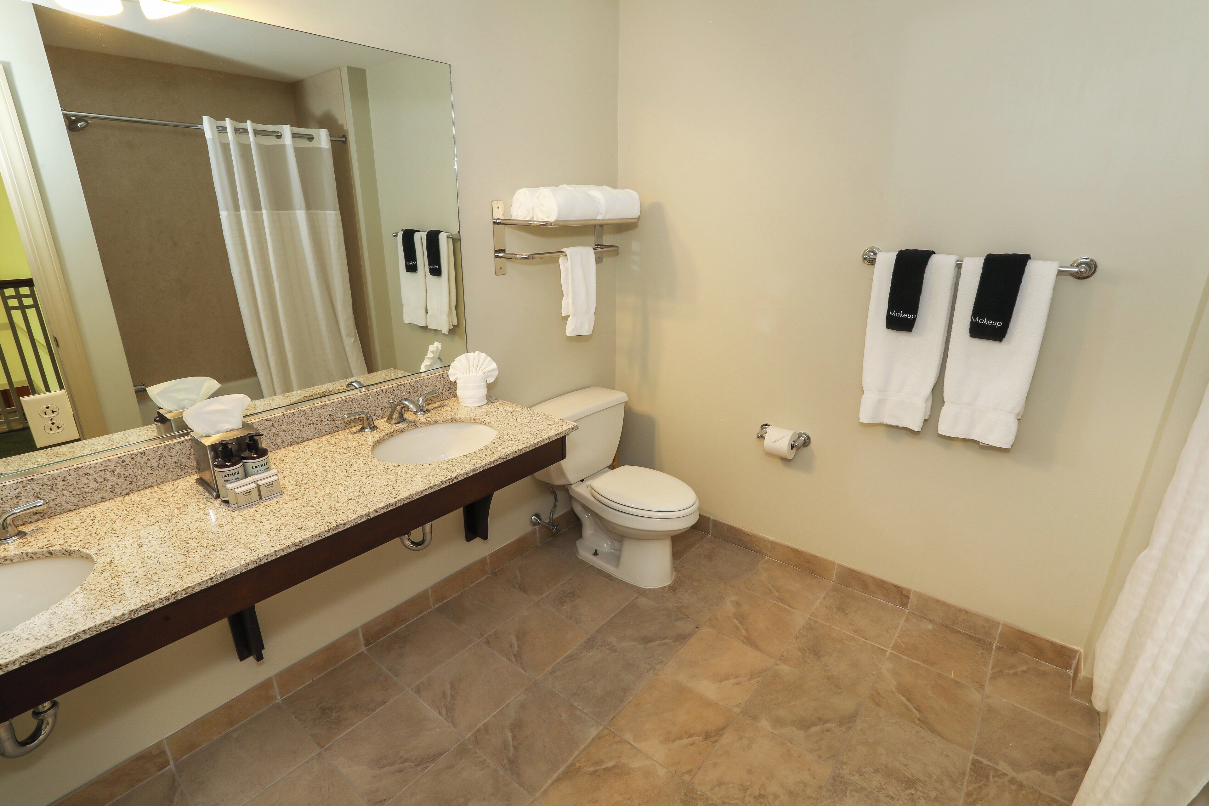 A bathroom with two sinks, a toilet, a shower, and a towel rack.