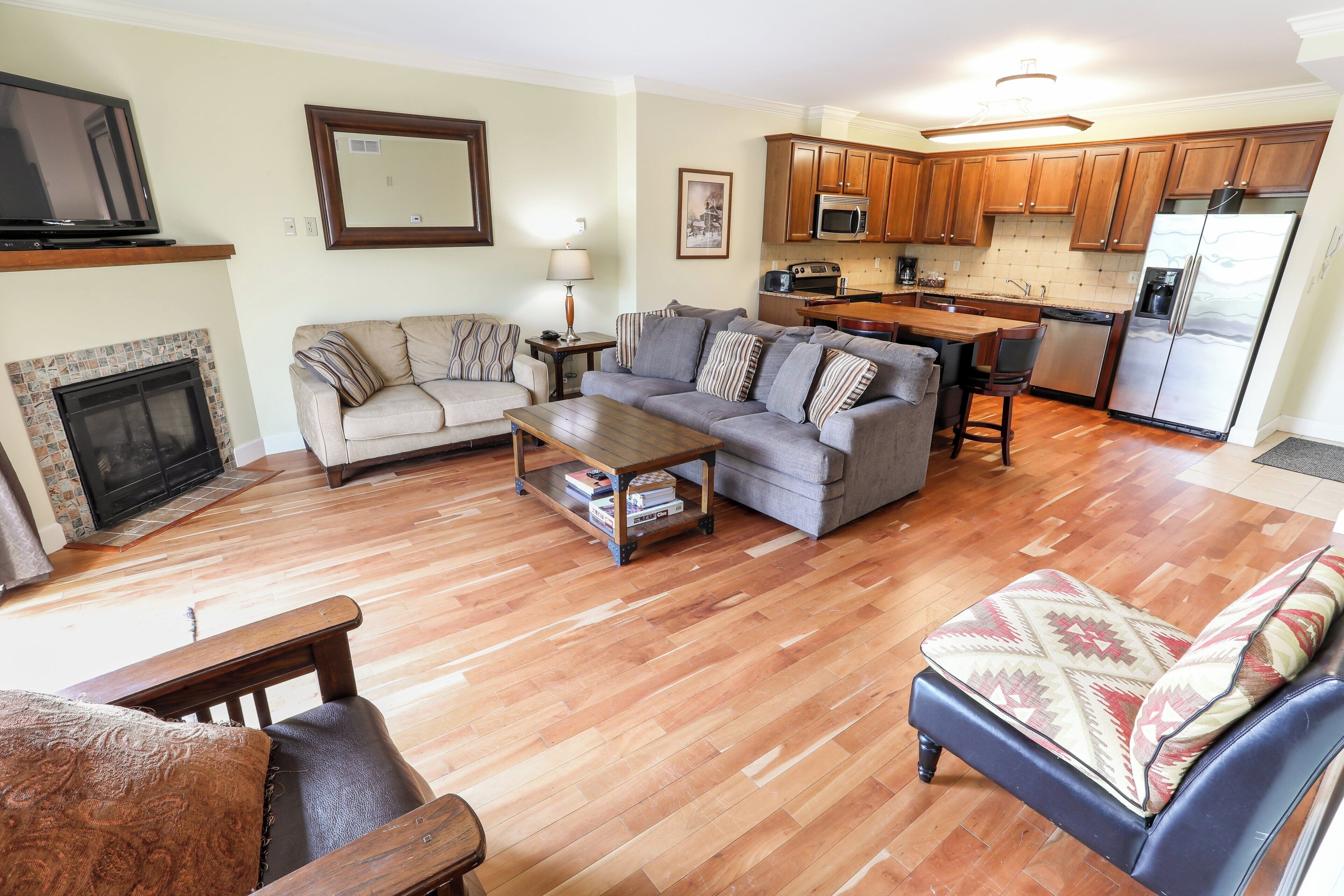 A living room with a fireplace, sofa, coffee table, and a dining area with chairs.