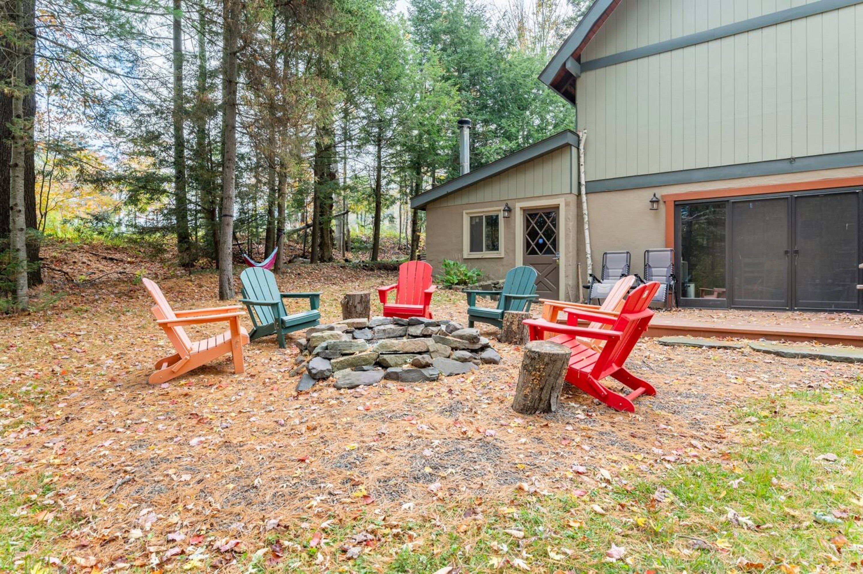 Una cabaña con un hogar de piedra rodeado de sillas Adirondack.