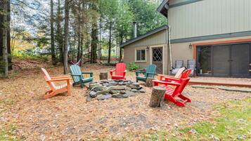 Una cabaña con un hogar de piedra rodeado de sillas Adirondack.