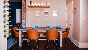 A dining area with a wooden table, four orange chairs, and a hanging light fixture. - Calming Seaside Sanctuary, pet friendly 2-blocks from beach (Galveston)
