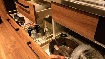 A kitchen with wooden cabinetry, a stainless steel range hood, and various kitchen utensils and cookware.