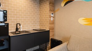A modern bathroom with a black countertop, a sink, and a shower area. - Grand Base Shianbashi (Nagasaki)