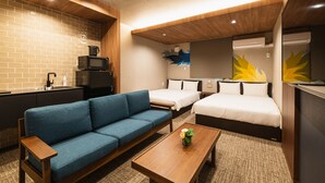 A modern hotel room with a blue sofa, two single beds, a wooden coffee table, a microwave, and a sink. - Grand Base Shianbashi (Nagasaki)