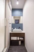 Um banheiro moderno com pia branca, espelho e parede com detalhes em azul.