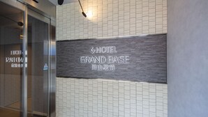 A hotel entrance with a sign reading "HOTEL GRAND BASE" and a tiled wall. - Grand Base Okayama Ekimae (Okayama)