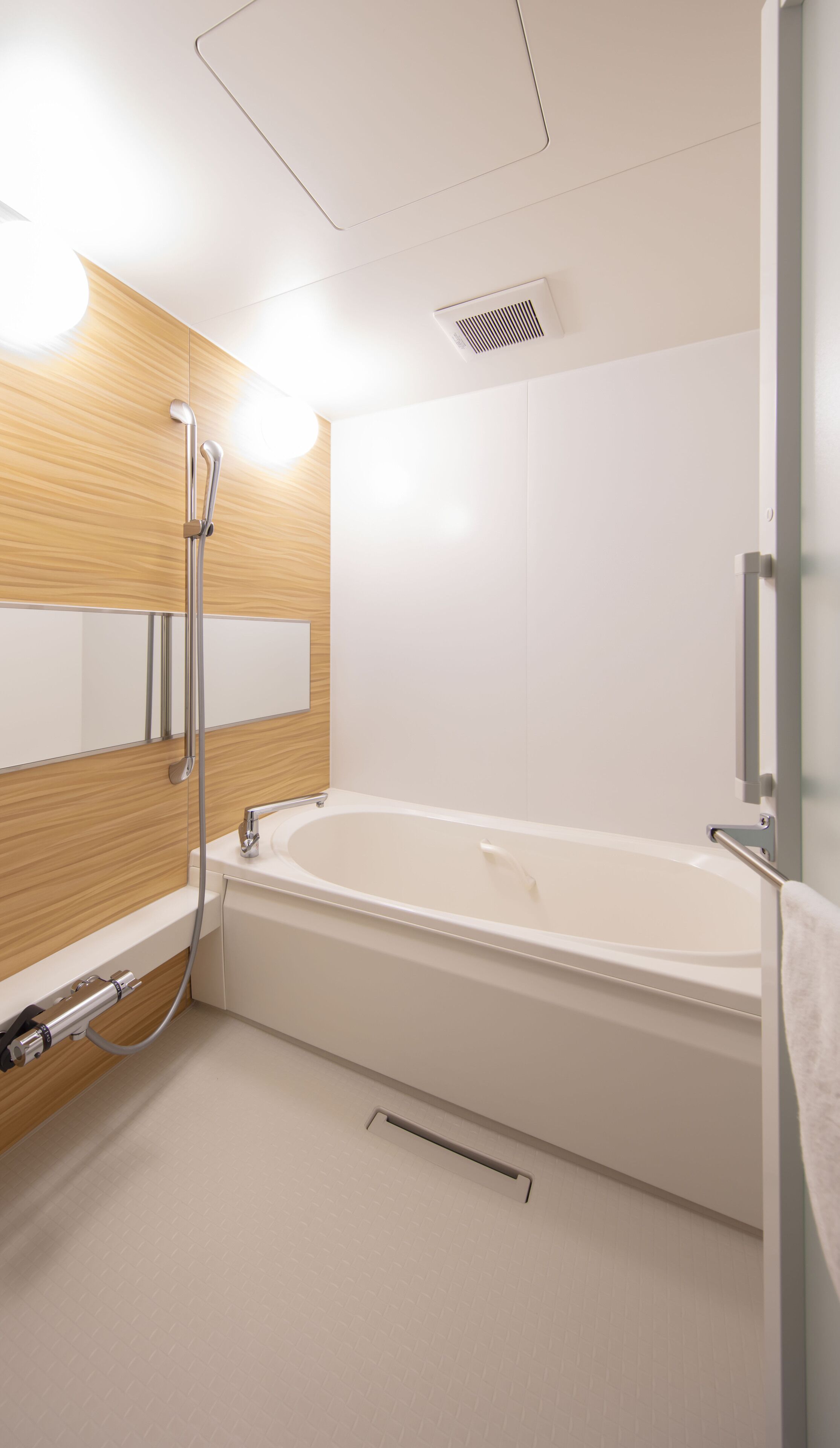 A modern bathroom with a bathtub, a wooden vanity, a mirror, and a shower head.
