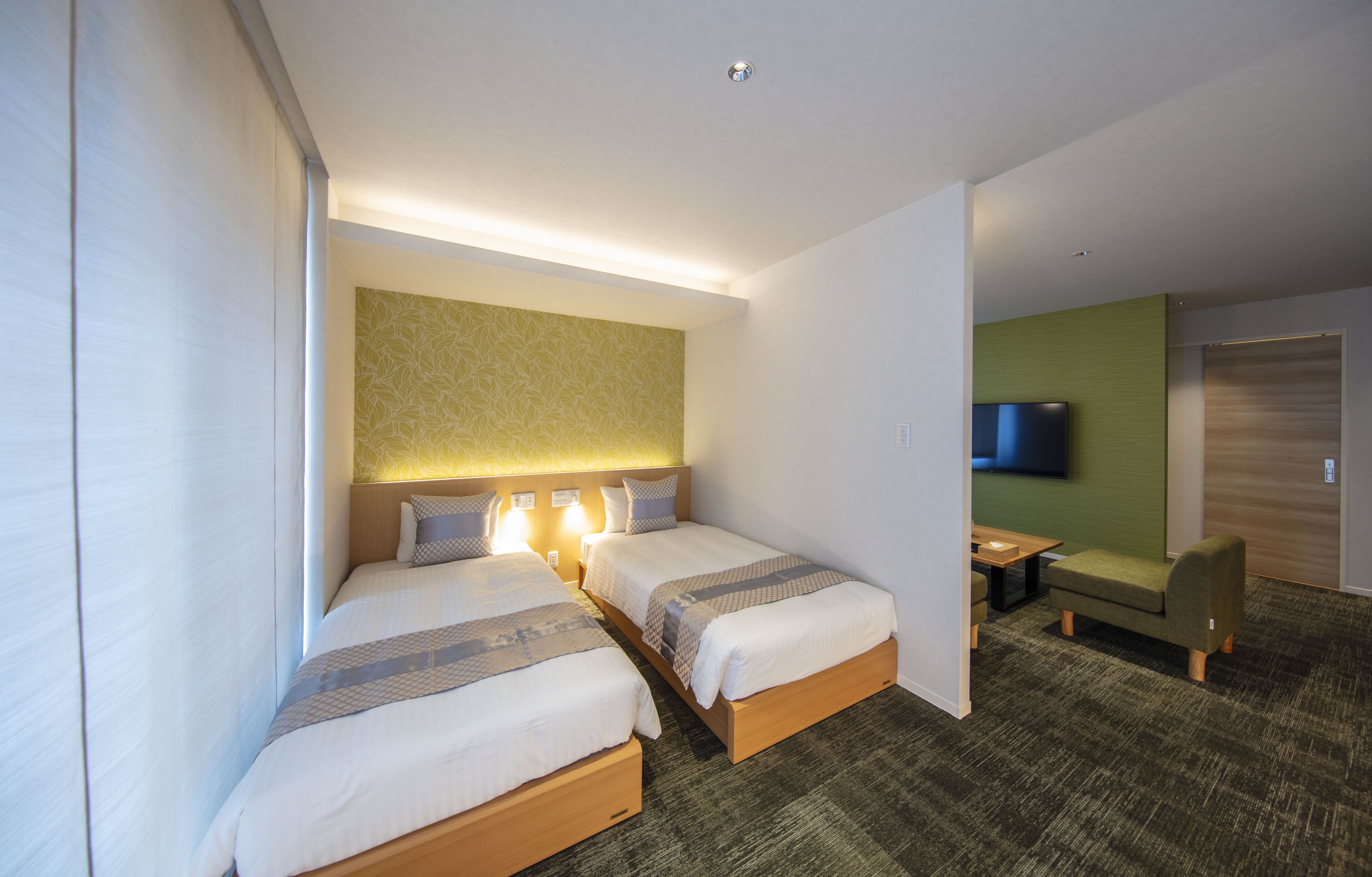 Une chambre d’hôtel avec deux lits, une petite table, un canapé et un téléviseur.