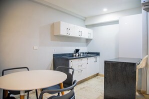 A compact kitchen with a white countertop, a sink, and a stove. There is a round table with chairs and a small island with a chair. - Hotelito del Mar Playa del Carmen (Playa del Carmen)