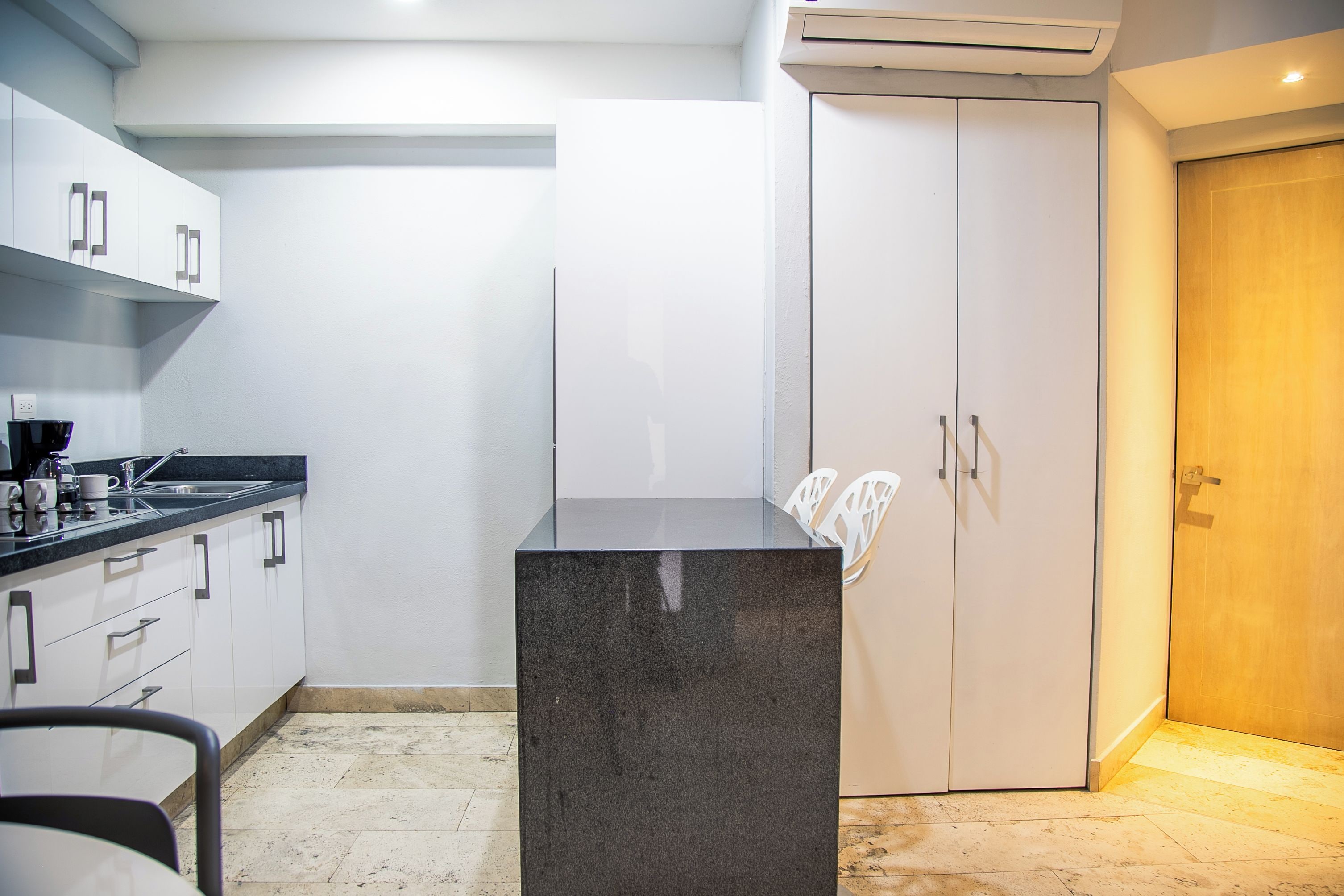 A modern kitchen with white cabinets, a black countertop, and a marble island.