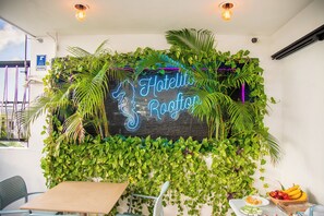A hotel reception area with a neon sign, indoor plants, a reception desk, and a fruit basket. - Hotelito del Mar Playa del Carmen (Playa del Carmen)