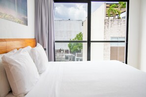 A hotel room with a large bed, a view of the city through a window, and a painting on the wall. - Hotelito del Mar Playa del Carmen (Playa del Carmen)
