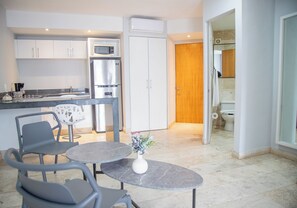A modern kitchen with a dining area, a refrigerator, a microwave, and a wooden door leading to a bathroom. - Hotelito del Mar Playa del Carmen (Playa del Carmen)