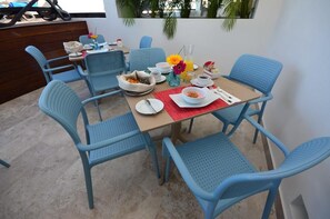 A dining area with a table set for two, blue chairs, and a red placemat. - Hotelito del Mar Playa del Carmen (Playa del Carmen)