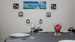 A dining table set with white plates, silverware, and wine glasses, with a decorative vase of flowers in the center. - Central Apartment Bucharest (București)