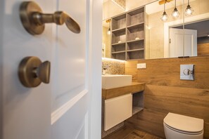 A modern bathroom with a wooden vanity, a mirror, and a white toilet.