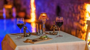Mesa posta com taças de vinho, um abajur e uma pequena escultura.
