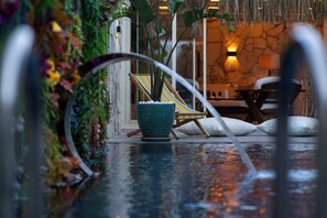 Área de piscina com uma cadeira e um vaso de planta.