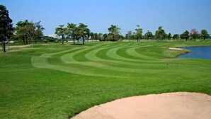Un campo da golf con un ostacolo d'acqua, bunker di sabbia e alberi.