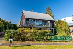 Een huis met twee verdiepingen en een balkon, omringd door groen.
