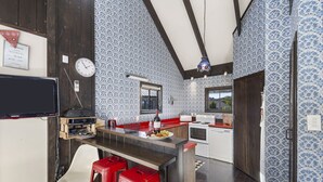 Une cuisine avec un bar en bois, des tabourets rouges, une horloge et un papier peint à motifs.